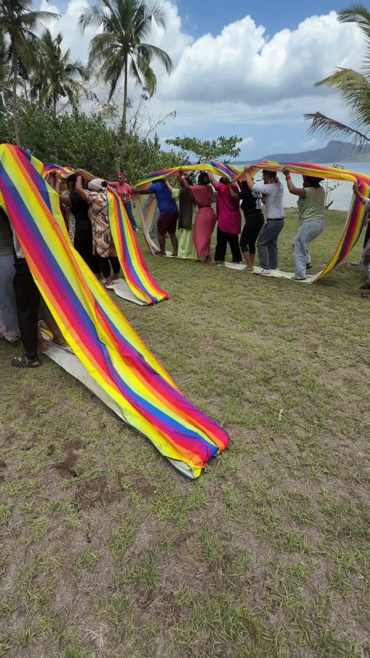 Parachute géant multicolore manipulé par une équipe à Mayotte, jeu collectif pour adultes et enfants